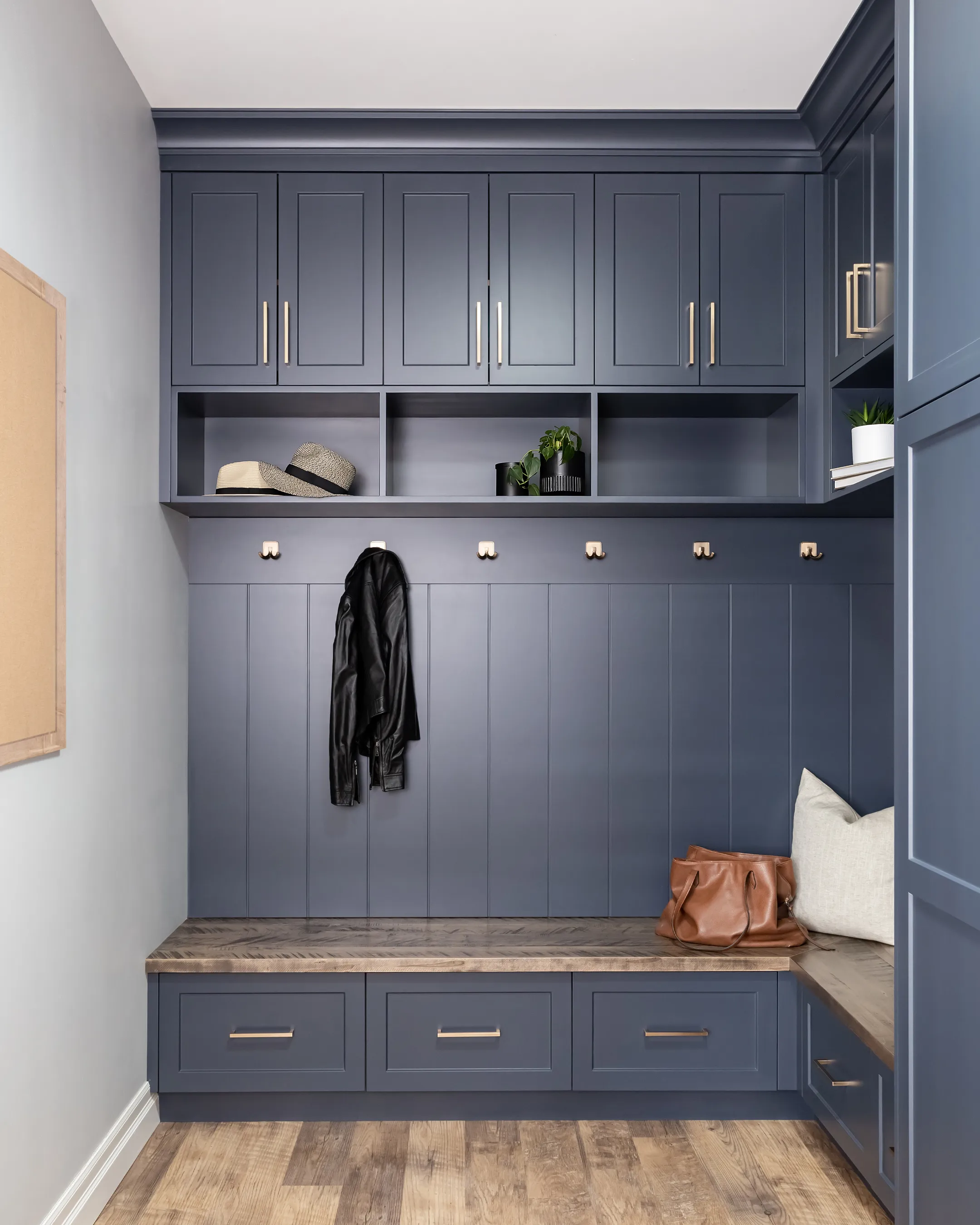 Custom navy mudroom with built-in bench, cubbies, and brass hardware